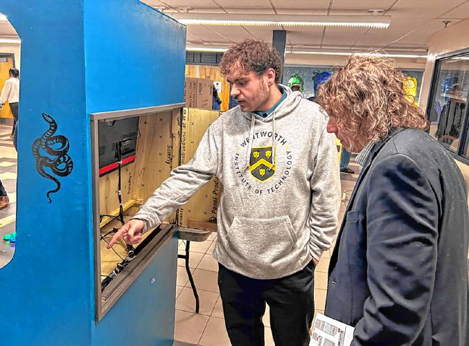 Merrimack Valley High School senior Clayton Ross shows superintendent Randy Wormald how the arcade Ross built for his senior project works.