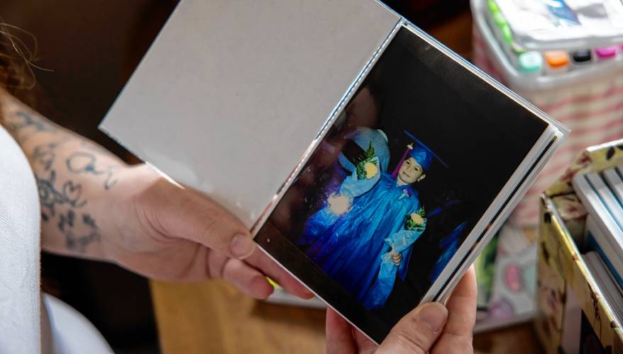 Brie Lamarche brings out a box of photographs from her living room in her apartment. The photographs help her connect back to memories of her childhood, including this photo of her in a graduation cap and gown.