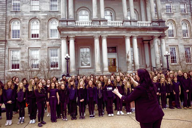 Weare Middle School choir director Serena Gorham conducts the group as they sing in front of the State House steps on Wednesday, March 27, 2024. Governor Chris Sununu signed a proclamation for celebration of Music in our Schools Month. Area schools rotated and sang and played in front of the steps.