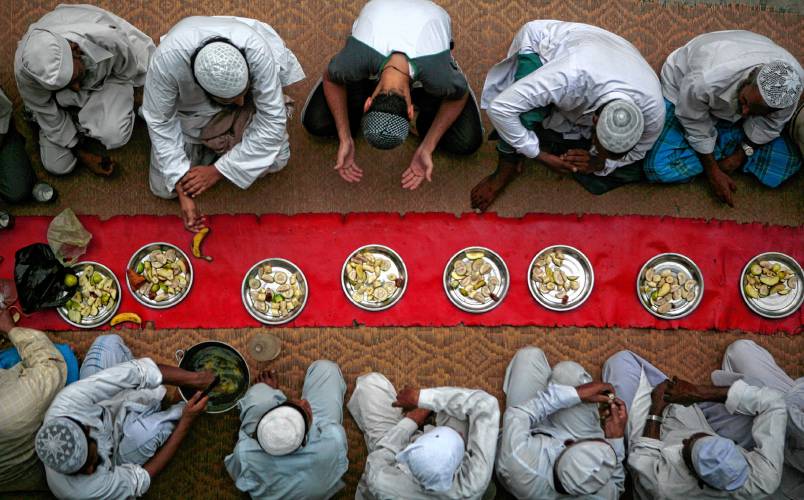 Plates with fruits are laid as fasting Muslims pray before breaking their fast on the first day of Ramadan in the compound of Jamia (Grand) Mosque in Amritsar, India, Sunday, Aug. 23, 2009.