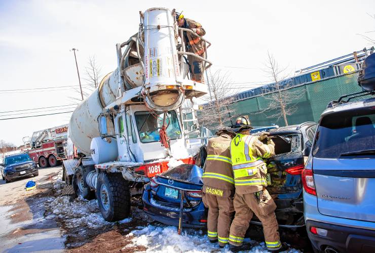 Concord firefighters break into the back of one of the vehicles that was hit by a Redimix cement truck on Monday, March 25, 2024. The parked car was empty and in the overflow lot of the Concord Bus Station off of Stickney Ave.