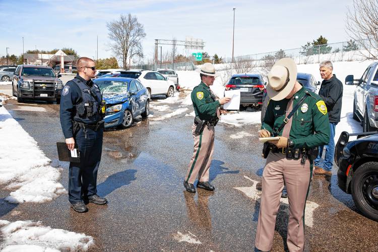 New Hampshire State Police officers work along with Concord Police after a Redimix cement truck slid off of I-93 South, broke through a fence (seen in backround) and hit numerous vehicles parked in the Concord Bus lot on Stickney Ave on Monday, March 25, 2024.