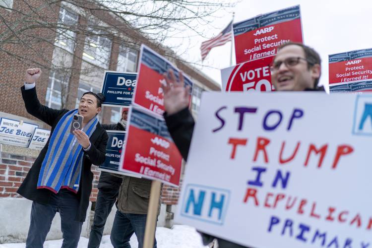 Former presidential candidate and businessman Andrew Yang, left, cheers while campaigning outside a polling site for Democratic presidential candidate Rep. Dean Phillips, D-Minn., as voting is underway in the New Hampshire presidential primary in Manchester, N.H., Tuesday, Jan. 23, 2024. (AP Photo/David Goldman)