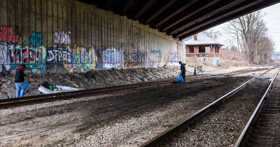 A group led by Concord city councilor Jeff Foote clean up along the railroad track underneath the Water Street bridge near the Common Man in downtown Concord.