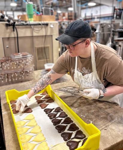 Chocolatiers at the Granite State Candy Shoppe factory on Hall St. Concord prepared chocolates for Valentine’s Day on Feb. 3. Kate Hayden prepped chocolate heart lollipops in molds.
